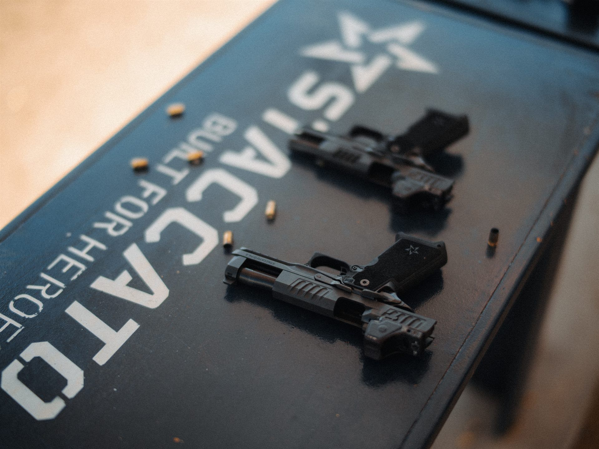 Two Staccato pistols and loose rounds on a painted Staccato bench