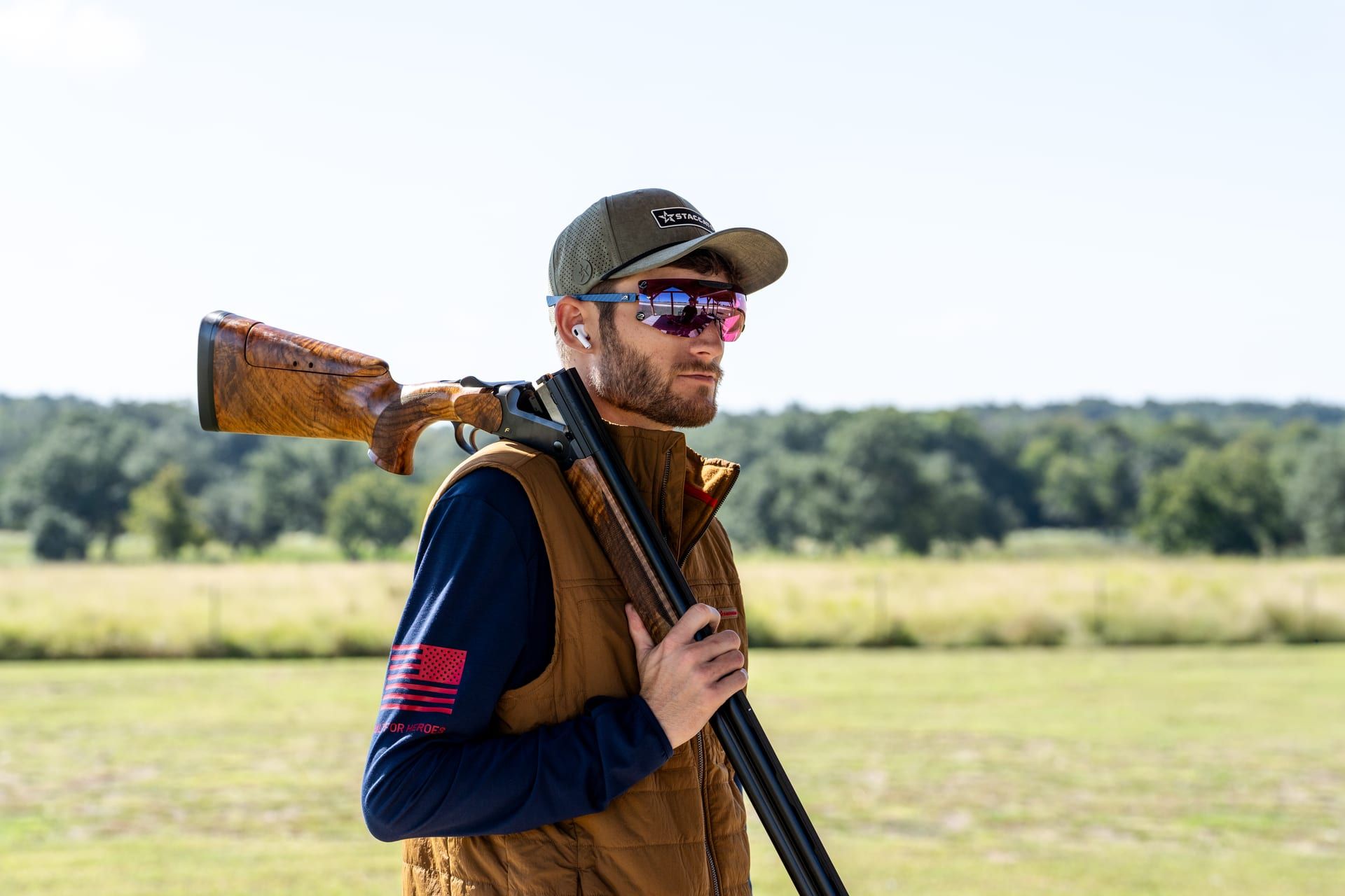 A shooter in a cap and shooting glasses on an open Texas field