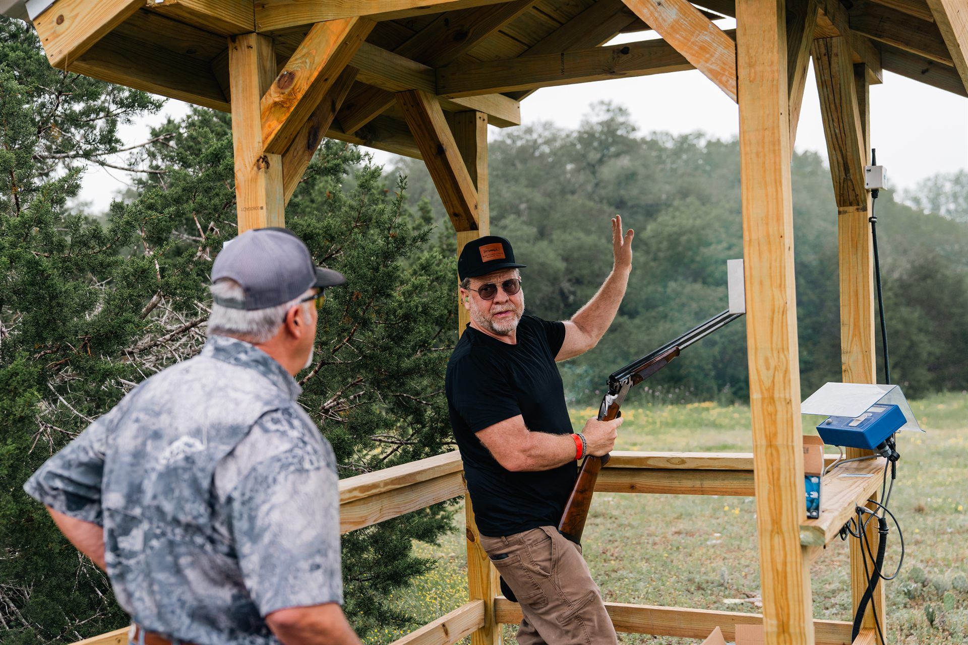 Two shooters at a covered stand on the Mesquite Flats sporting clays course at Staccato Ranch Texas.